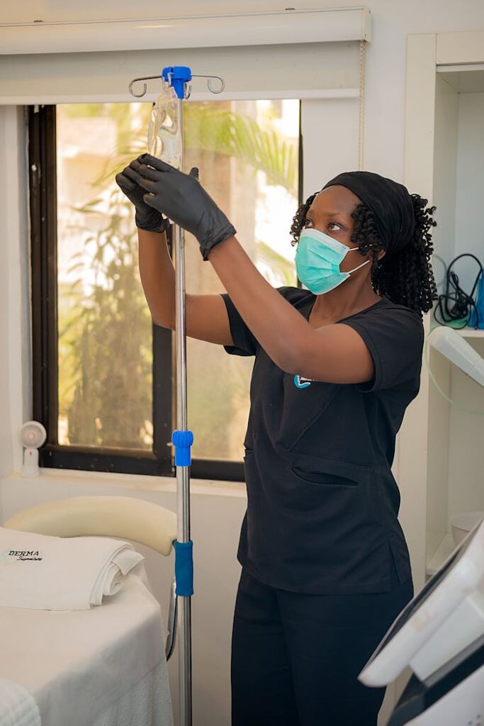 Female healthcare worker in clinical setting adjusting an IV drip.